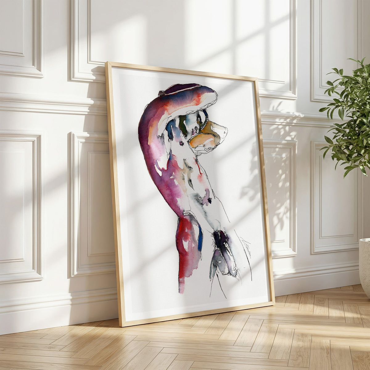 Male nude watercolor art print by Brenden Sanborn in a light wood frame leaning against a white paneled wall in a sunlit room