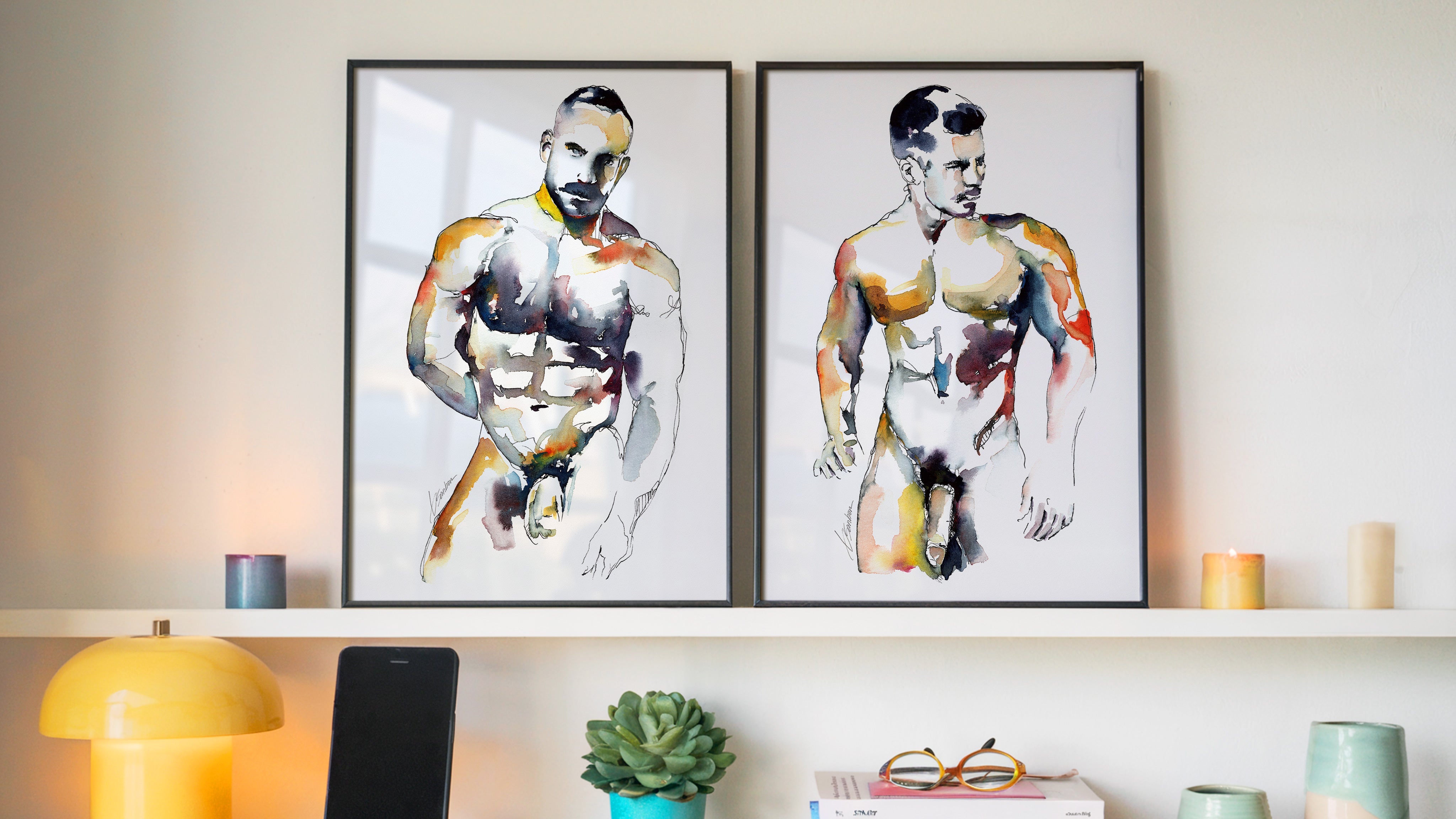 Male nude watercolor art prints by Brenden Sanborn, two framed figure paintings displayed on a shelf in a modern home