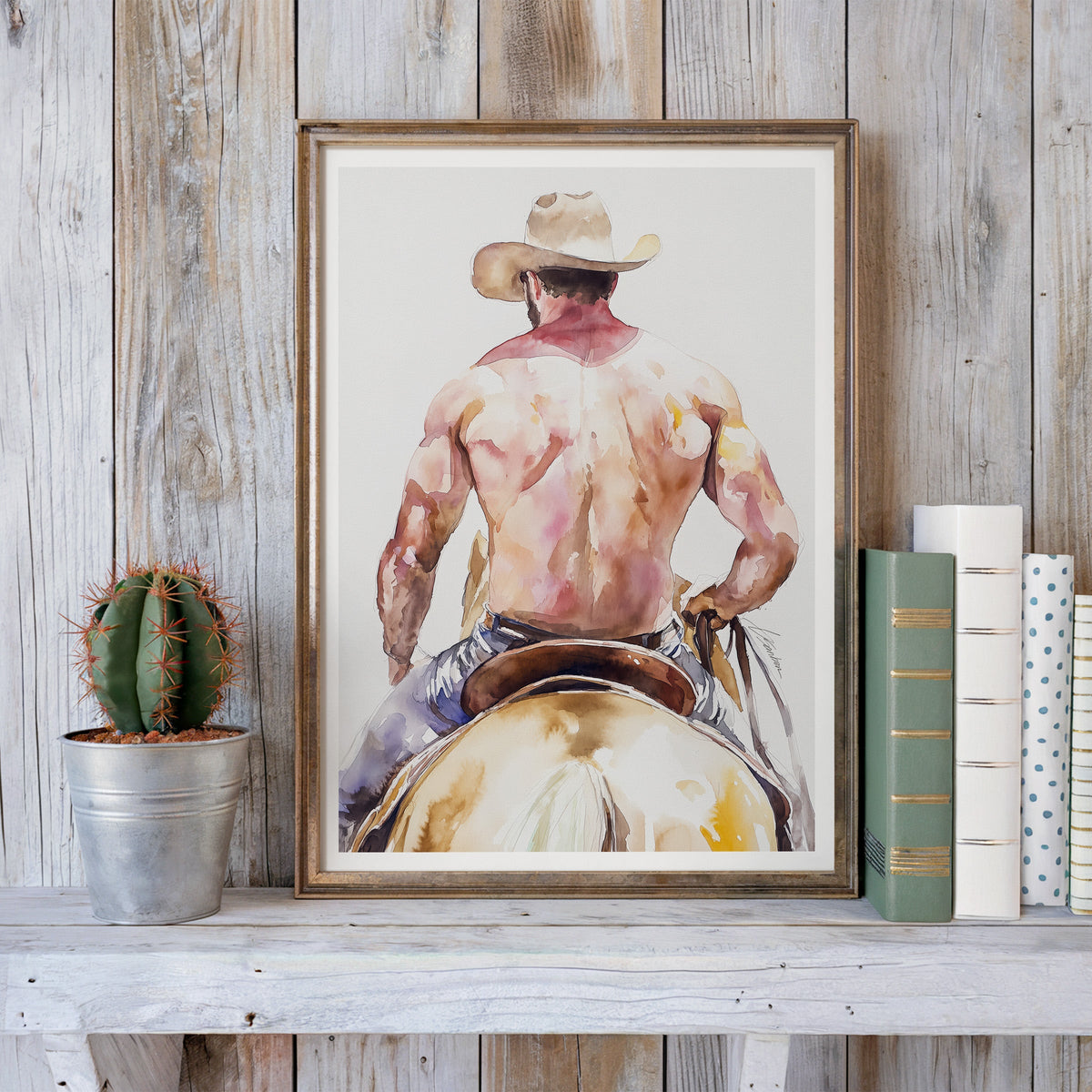Cowboy on horseback watercolor art print in a wood frame with books and a cactus, Saddle Up collection by Brenden Sanborn