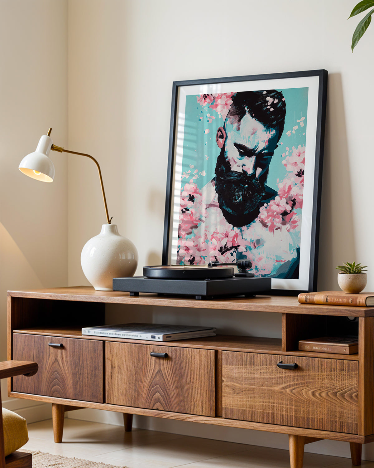 Blush Season art print in a black frame leaning on a walnut sideboard beside a record player