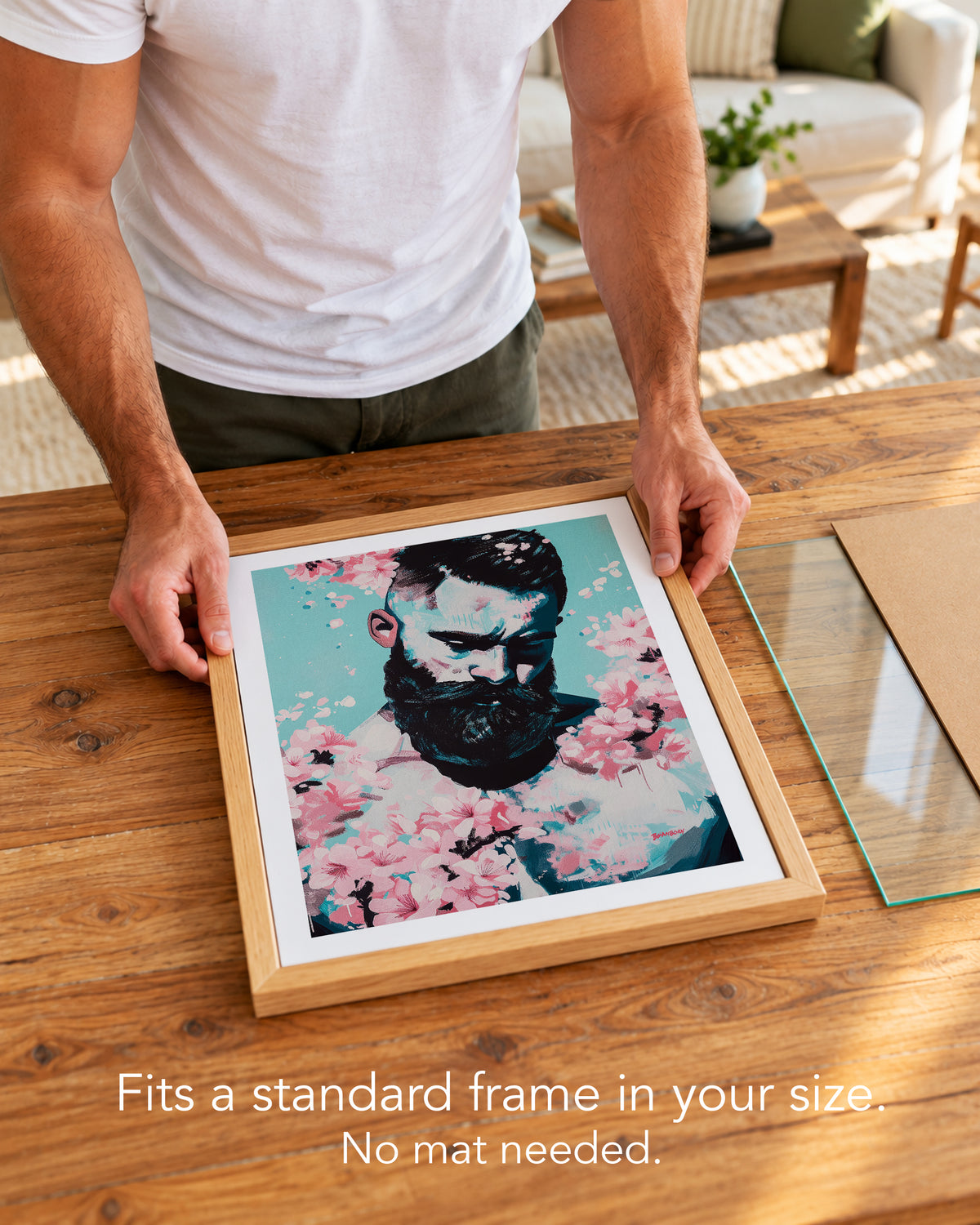 A man placing the Blush Season paper art print with a white border into a standard wood frame, no mat needed