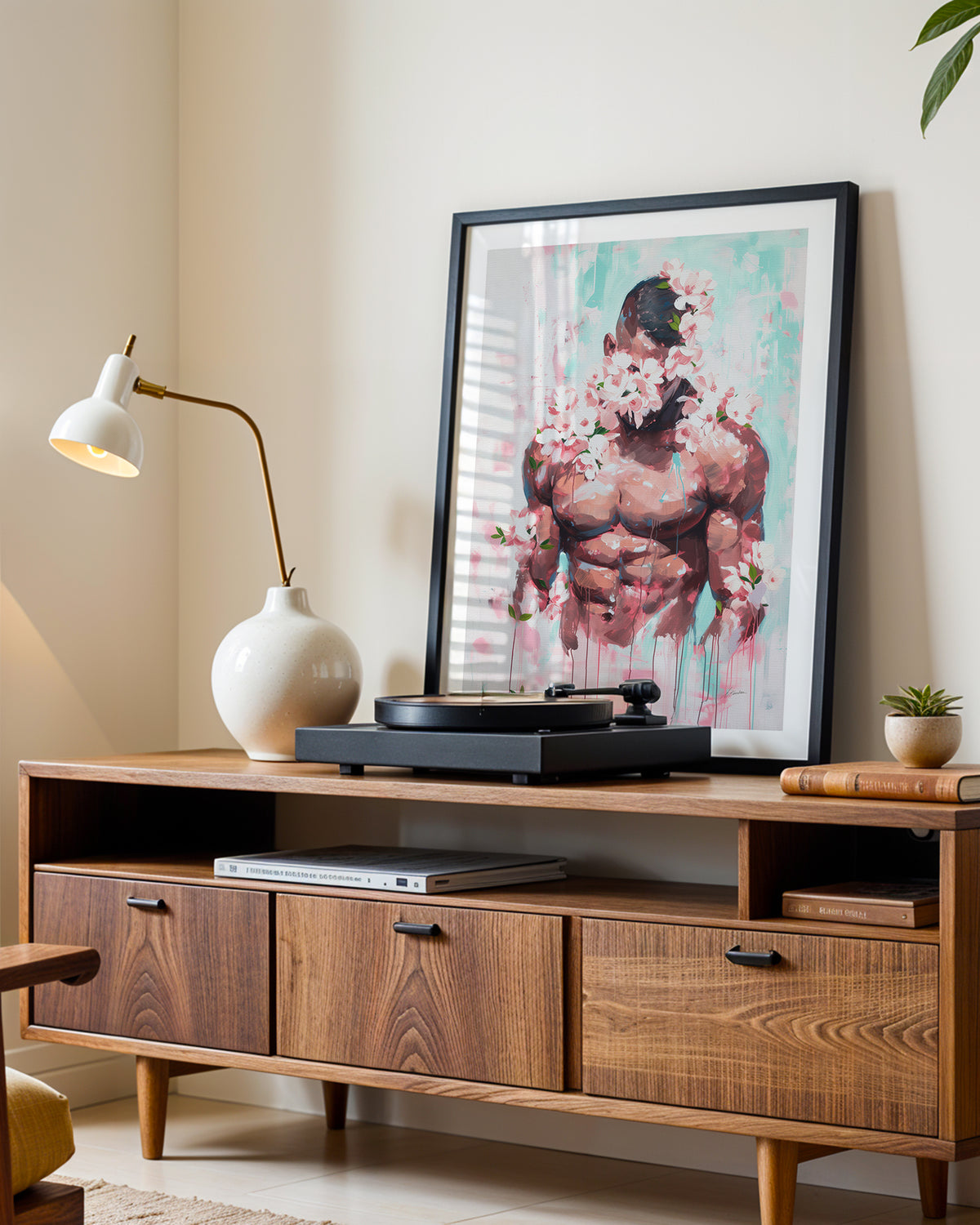 Pink Static art print in a black frame leaning on a walnut sideboard beside a record player