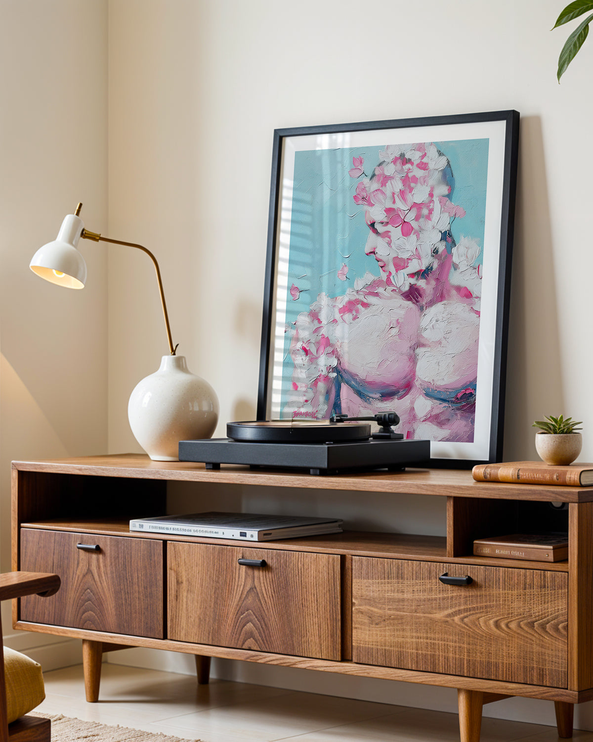 Rose Plaster art print in a black frame leaning on a walnut sideboard beside a record player