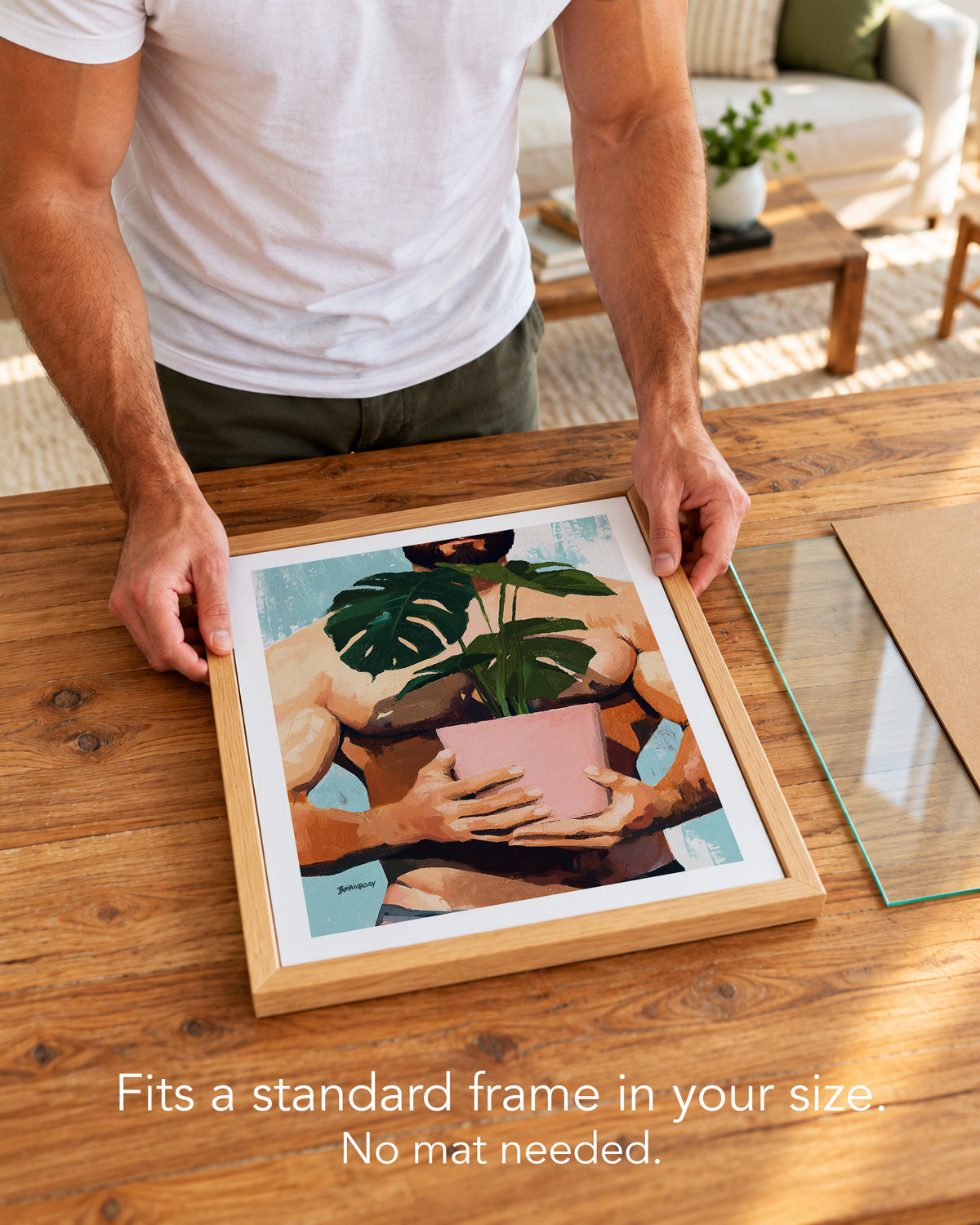 A man placing the Small Jungle paper art print with a white border into a standard wood frame, no mat needed