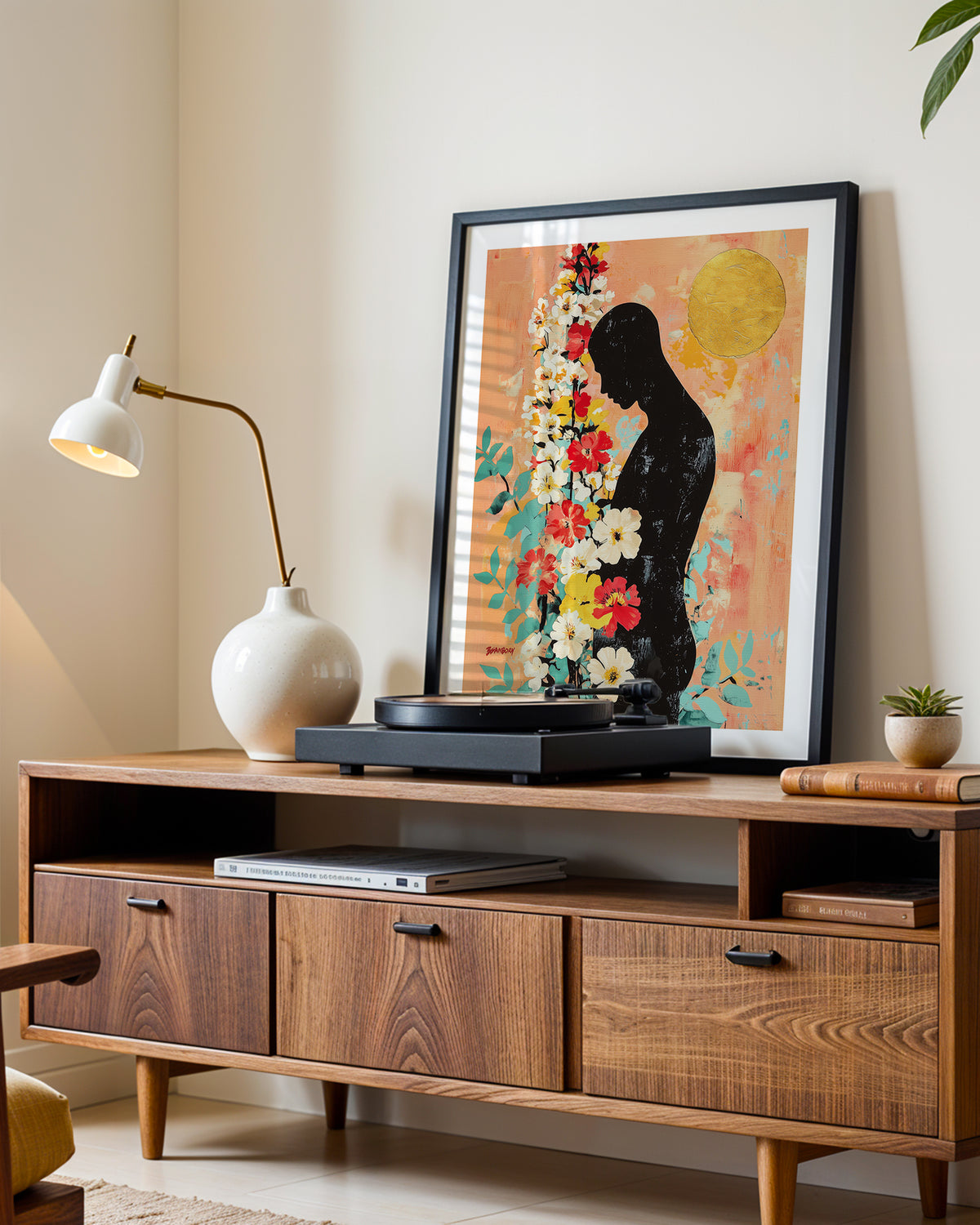 Bowed Light art print in a black frame leaning on a walnut sideboard beside a record player