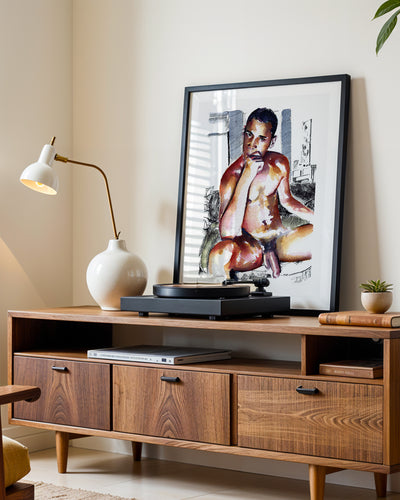 Magnitude art print in a black frame leaning on a walnut sideboard beside a record player