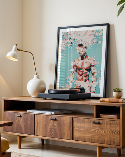 Falling Pink art print in a black frame leaning on a walnut sideboard beside a record player