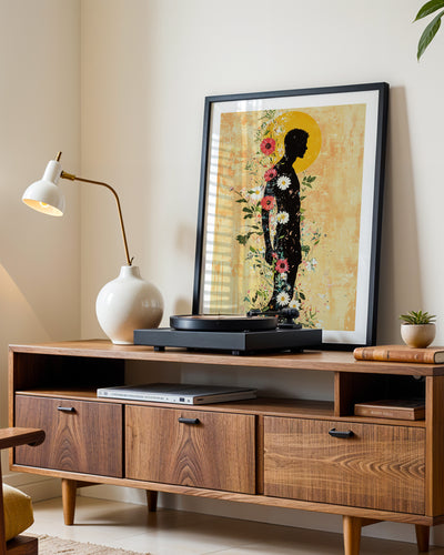 Inner Garden art print in a black frame leaning on a walnut sideboard beside a record player