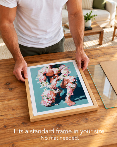 A man placing the Low Bloom paper art print with a white border into a standard wood frame, no mat needed