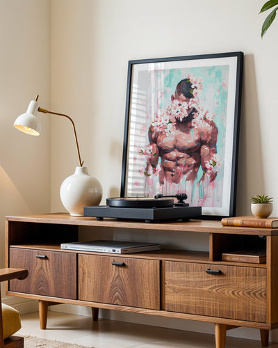 Pink Static art print in a black frame leaning on a walnut sideboard beside a record player