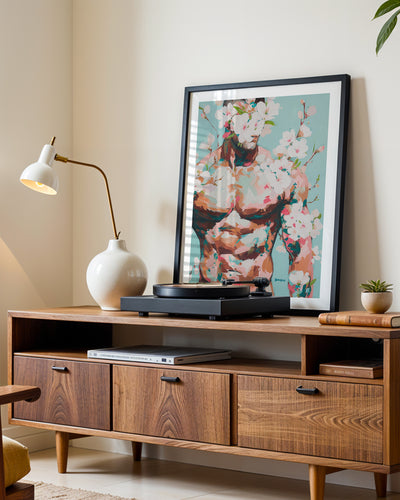 Quiet Orchard art print in a black frame leaning on a walnut sideboard beside a record player