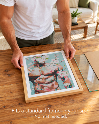 A man placing the Quiet Orchard paper art print with a white border into a standard wood frame, no mat needed