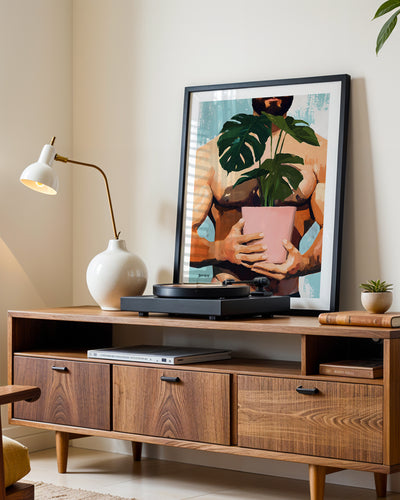 Small Jungle art print in a black frame leaning on a walnut sideboard beside a record player