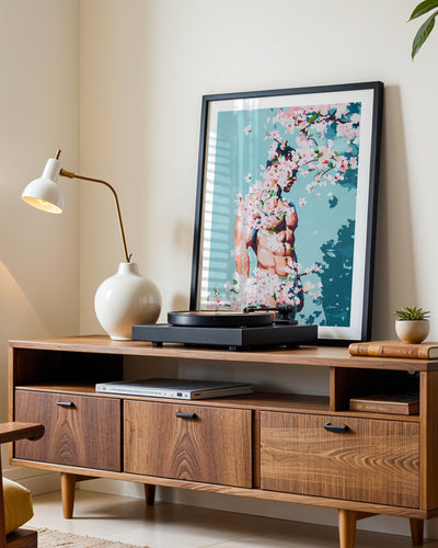 Under Branches art print in a black frame leaning on a walnut sideboard beside a record player