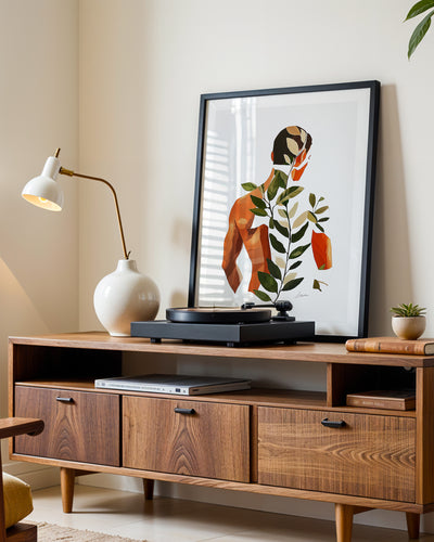 Vine Memory art print in a black frame leaning on a walnut sideboard beside a record player