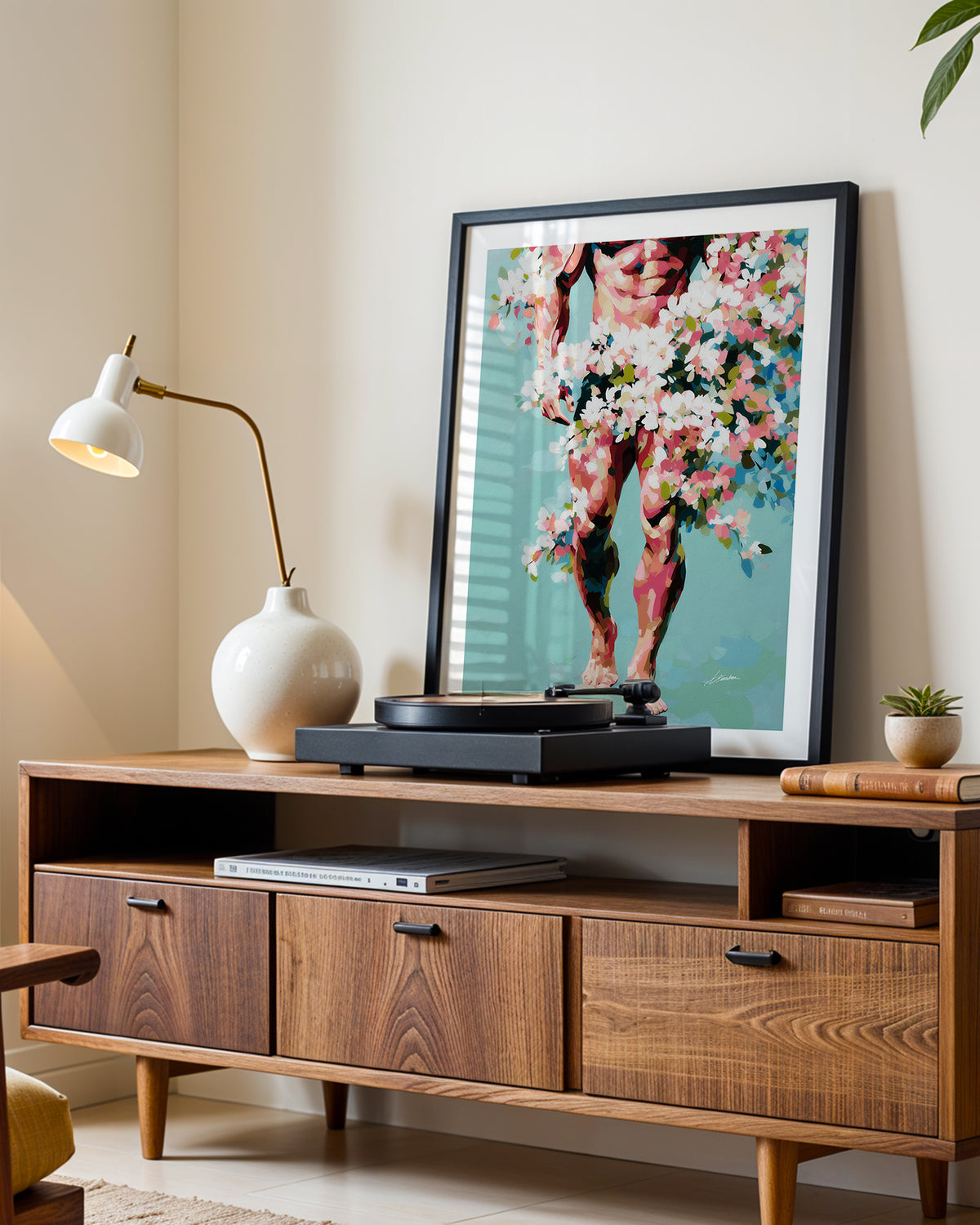 Walking Spring art print in a black frame leaning on a walnut sideboard beside a record player