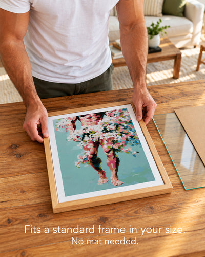 A man placing the Walking Spring paper art print with a white border into a standard wood frame, no mat needed