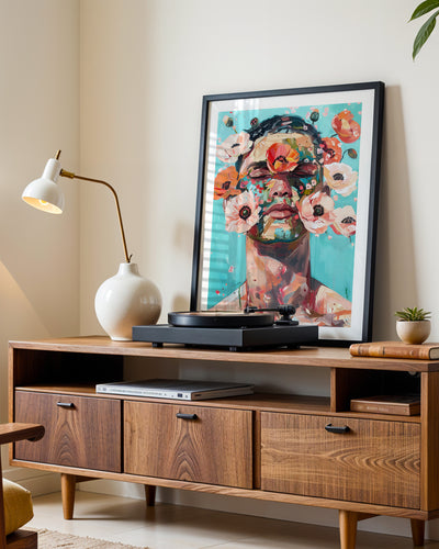 Wild Mask art print in a black frame leaning on a walnut sideboard beside a record player